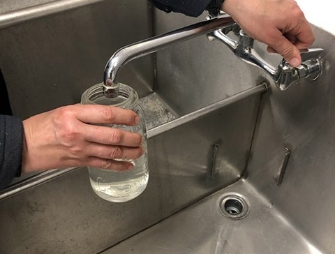 farmer pours cold water into jar for egg test