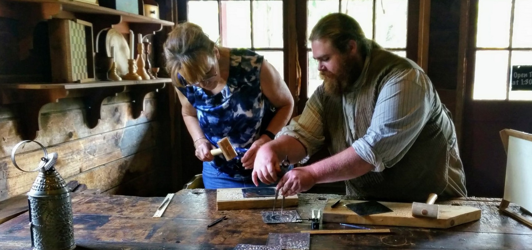 woman learns tinsmithing skills from instructor in DIY Heritage Trades workshop at the Village at Black Creek