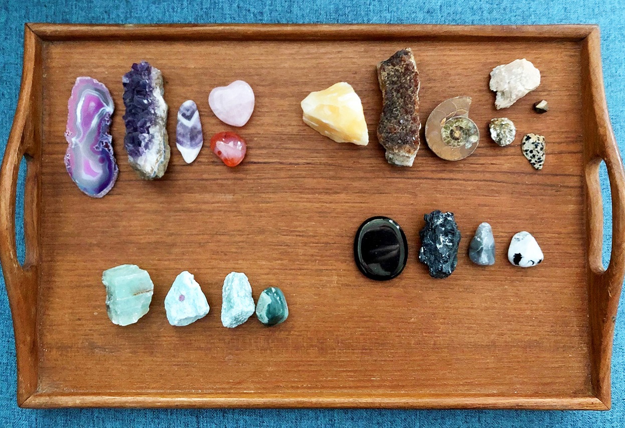 a collection of unusual rocks organized by colour on a wooden tray