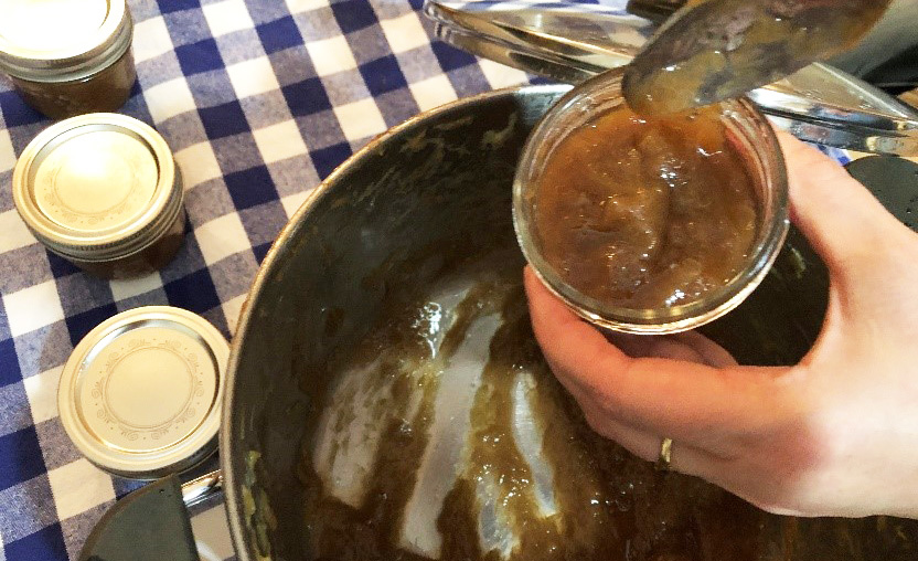 cook scoops rhubarb jam into jars