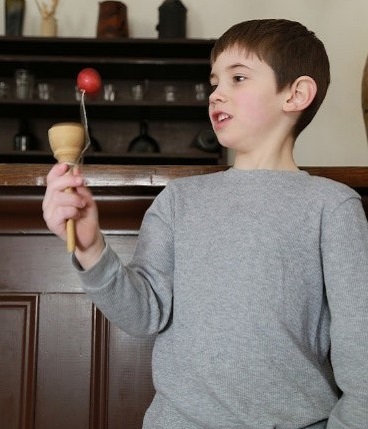 boy plays with ball and cup game at Black Creek Pioneer Village