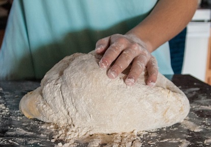 baker kneads dough to make bread