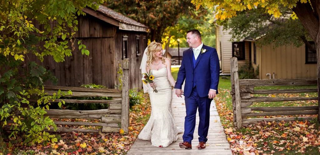 newlyweds pose for wedding photograph against autumn backdrop at Black Creek Pioneer Village