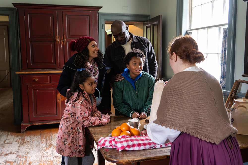 a family interact with an interpreter in the old house kitchen