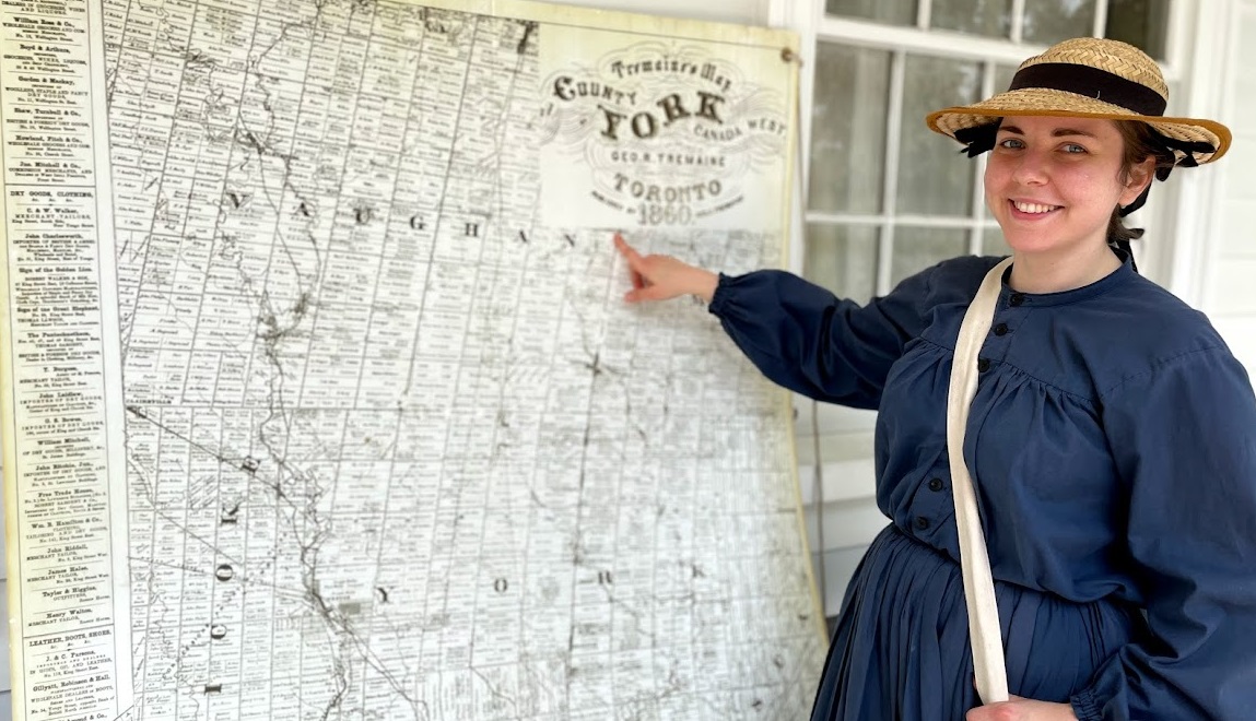 history actor in period costume studies historic map of 19th century Toronto area at Black Creek Pioneer Village