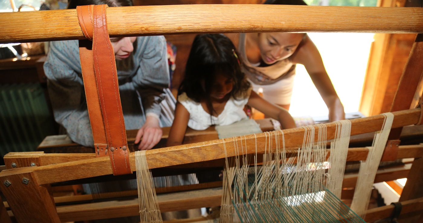 student learns how to weave wool on a loom