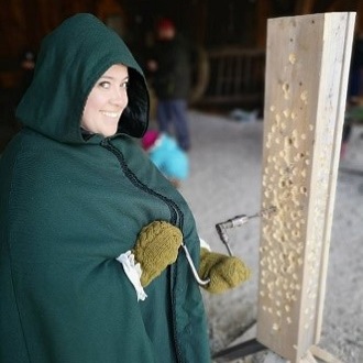 costumed educator at Black Creek Pioneer Village demonstrates technique for tapping maple trees to yield sap