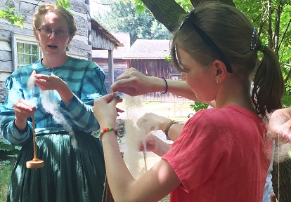 young visitors to Black Creek Pioneer Village get a lesson in working with wool from a costumed educator