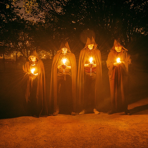 hooded figures carry candles on the darkened streets of the Village at Black Creek