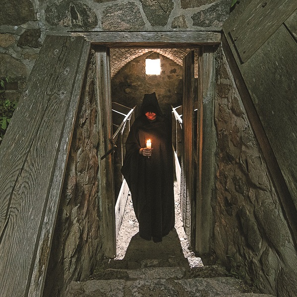 ominous hooded figure lurks in the doorway of the cider house at Black Creek Pioneer Village