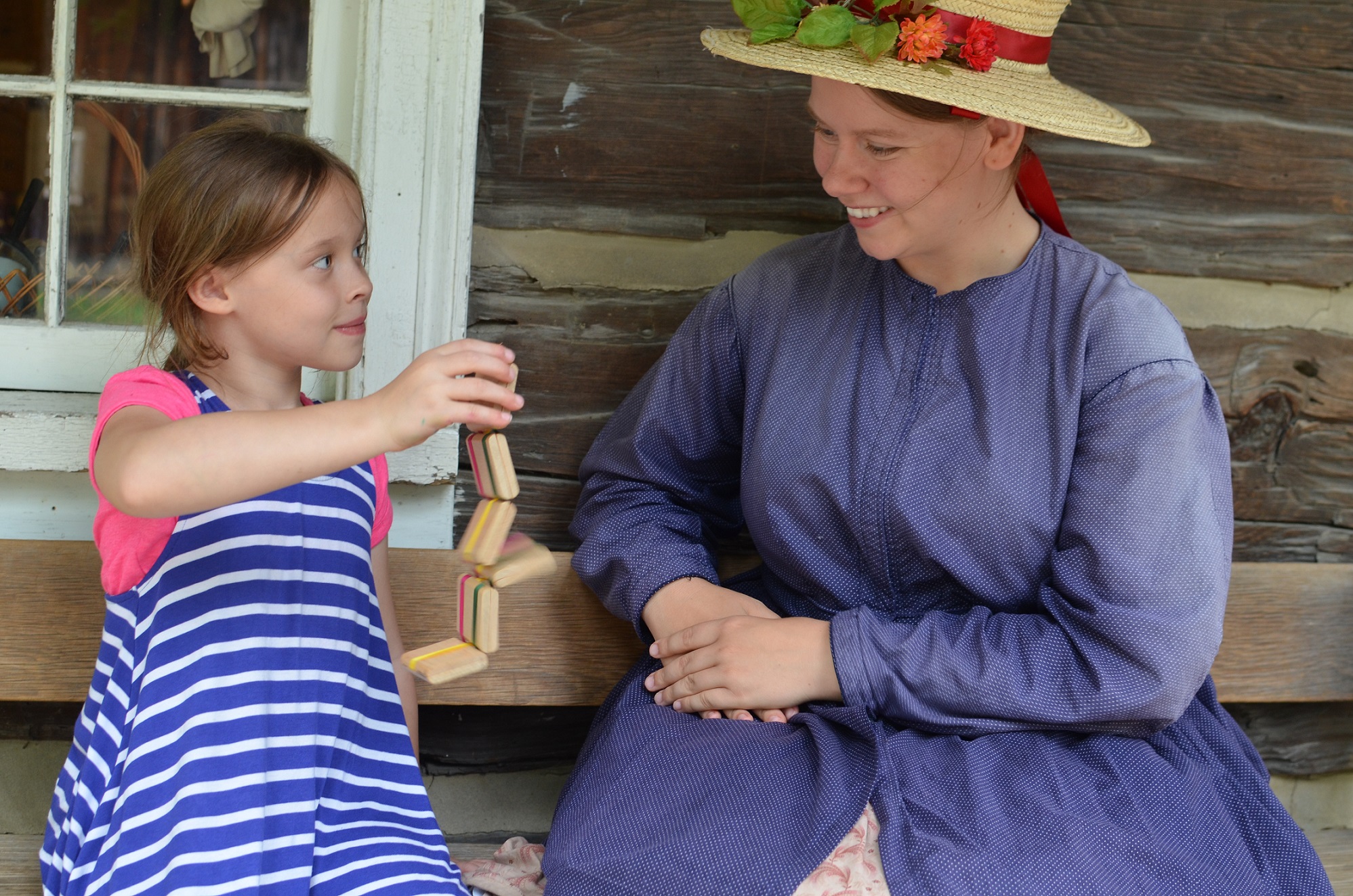 costumed educator introduces student to Victorian wooden toy at Black Creek Village