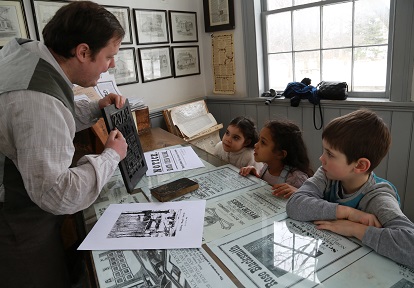 educational interpreter at Black Creek printing office shows young visitors the 19th century method of typesetting