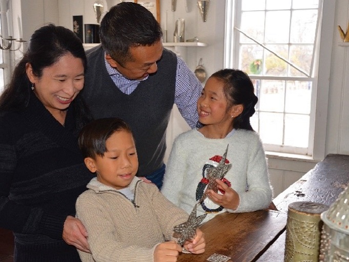 young family explores the tinsmith shop at Black Creek Village