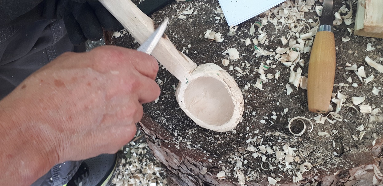 artisan carves a wooden spoon