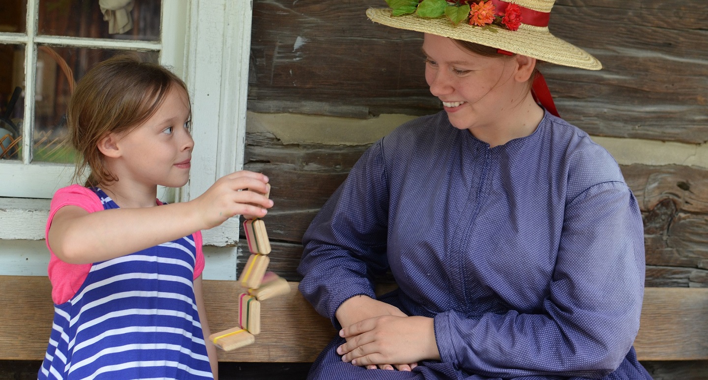 costumed educator at Black Creek Pioneer Village introduces a young visitor to traditional 19th century toys and games