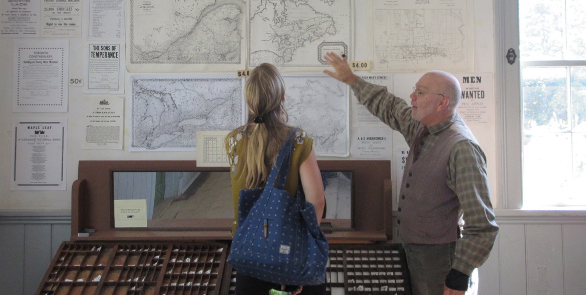 a Village at Black Creek volunteer greets a visitor to the printing shop