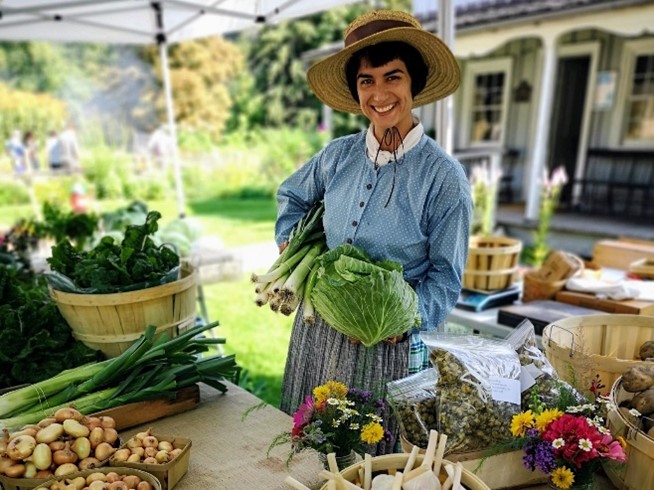 history actor in costume displays freshly harvested vegetables during Black Creek Pioneer Village Fall Festival