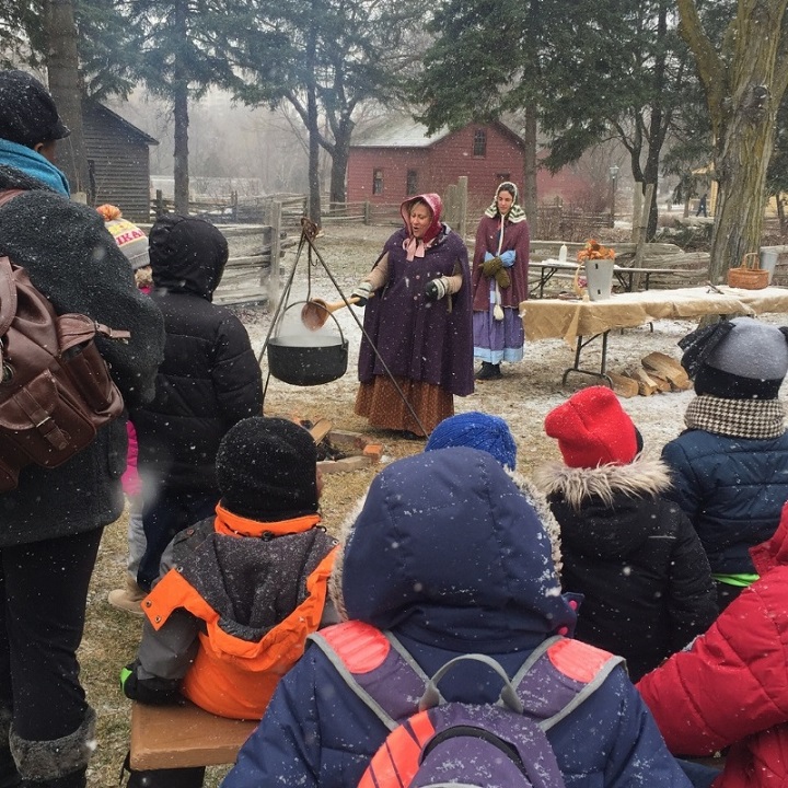 costumed educator at Black Creek Pioneer Village demonstrates traditional method for making maple syrup