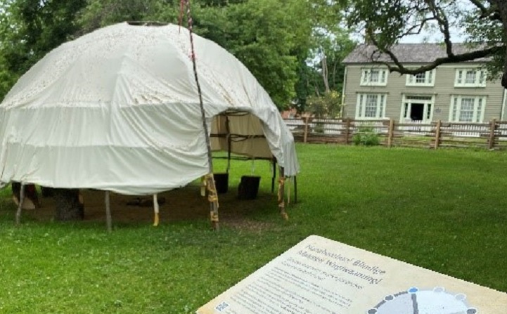 a wiigiwaam accompanied by an informational panel at Black Creek Pioneer Village