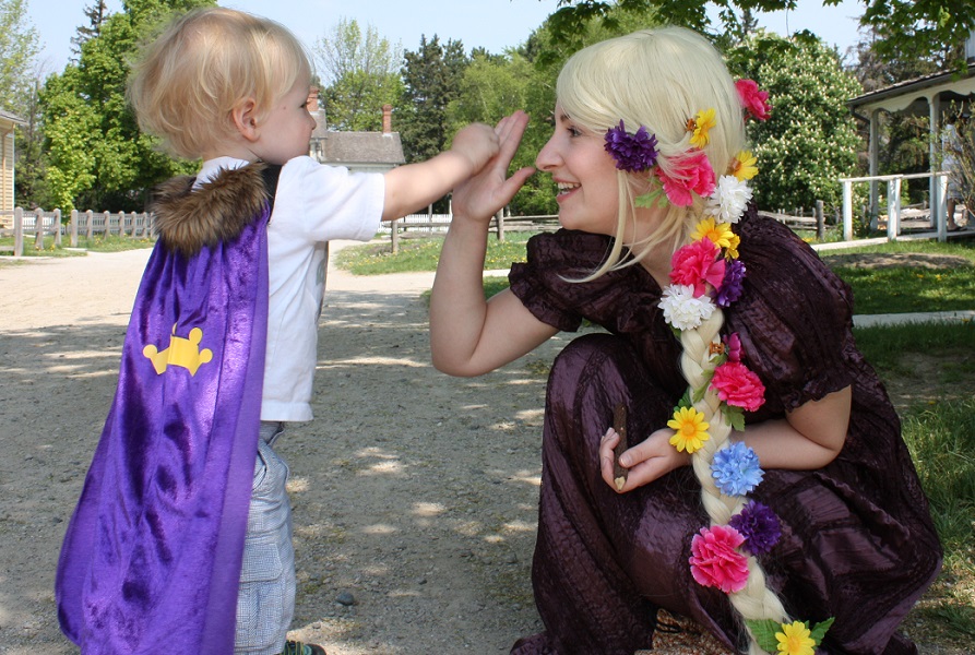 a history actor in a fairy-tale costume greets a young visitor to Black Creek Village