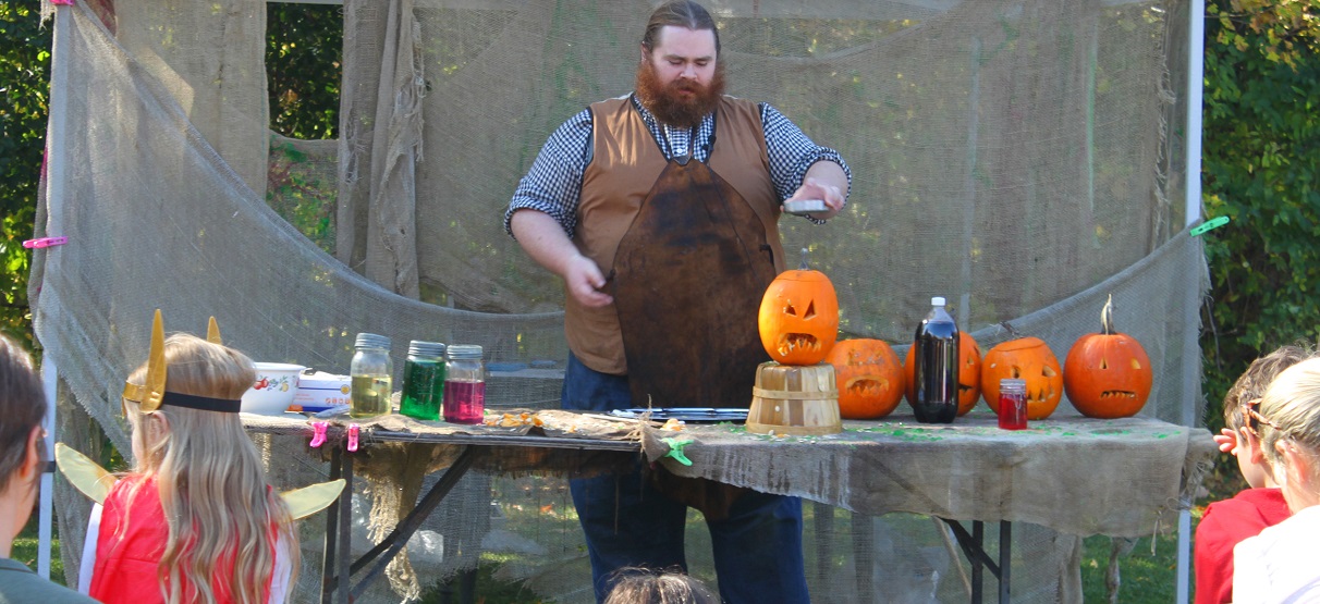 a performer at the Village at Black Creek Halloween event enterains children with a slimy science show featuring jack-o-lanterns and magic potions