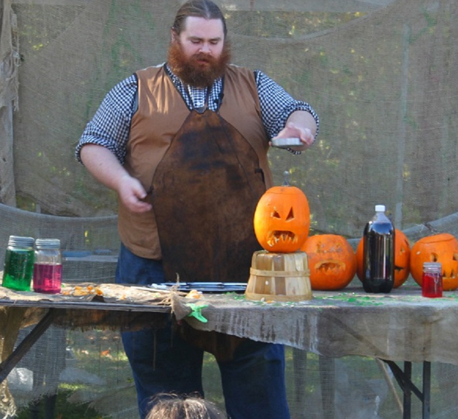 a performer at the Village at Black Creek Halloween event enterains children with a slimy science show featuring jack-o-lanterns and magic potions