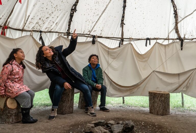 a young family explores a traditional Wiigiwaam at the Village at Black Creek