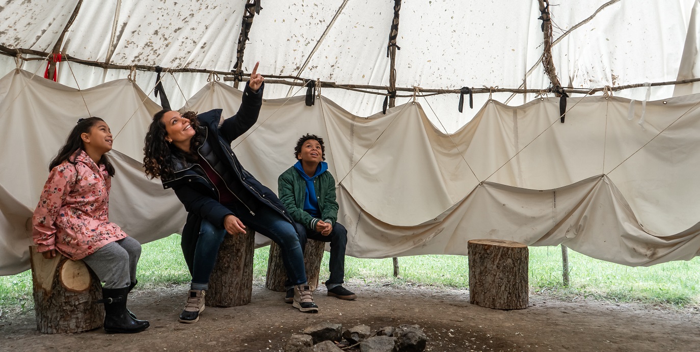 mother and children discover a traditional Ojibwe wiigiwaam at the Village at Black Creek