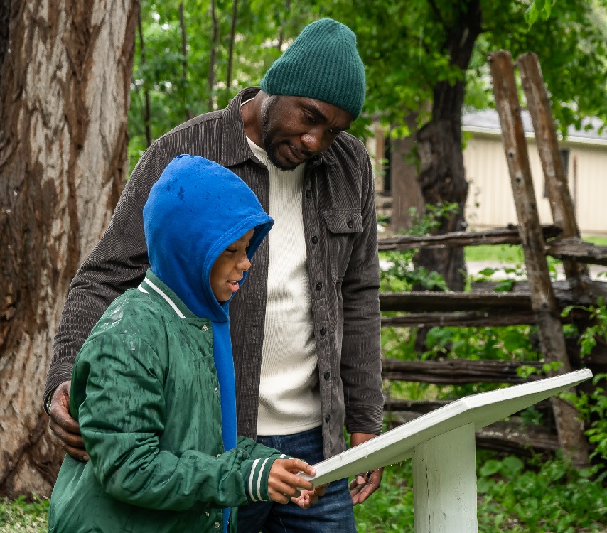 father and son study informative signage as they explore the Village at Black Creek