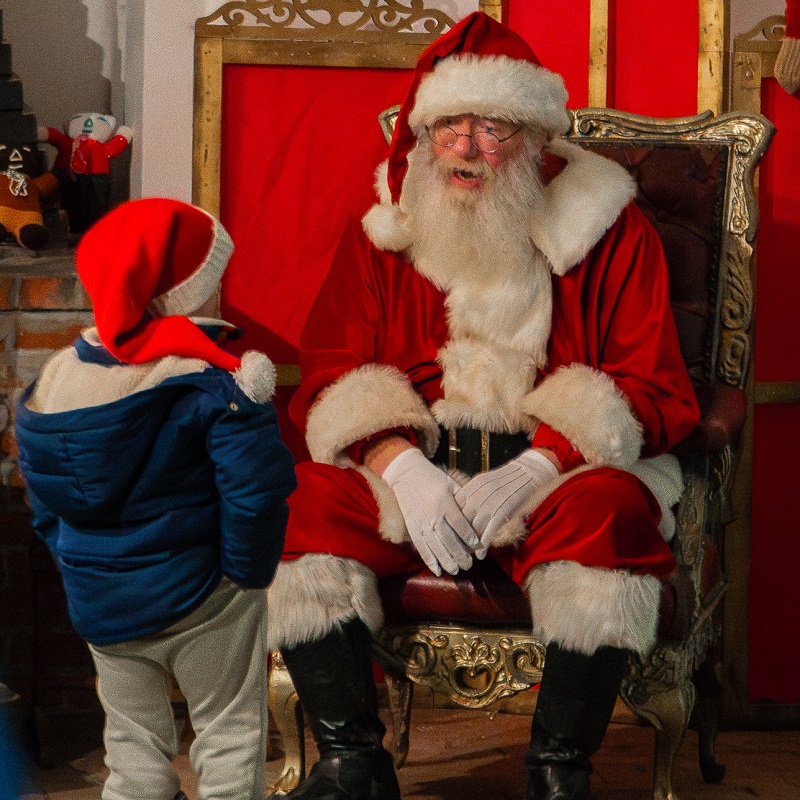 Santa Claus welcomes a young visitor to his workshop at The Village at Black Creek