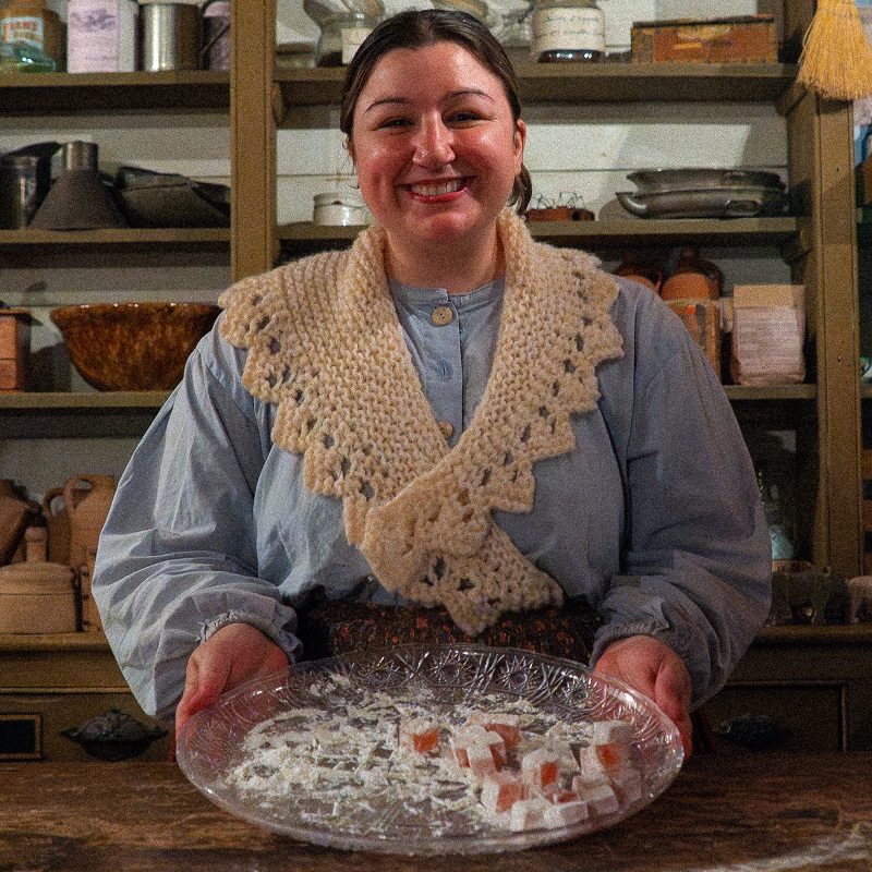 a history actor in 19th century clothing offers up a selection of traditional Victorian holiday treats at The Village at Black Creek