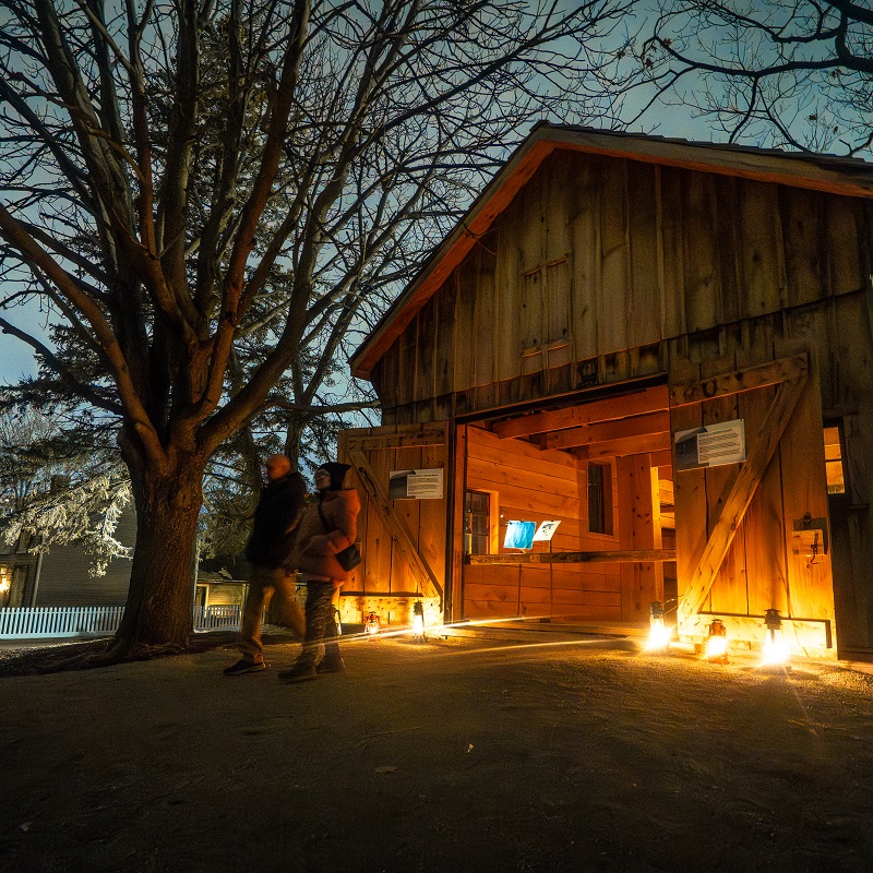 visitors explore The Village at Black Creek by lamplight during the Festive Nights holiday celebration