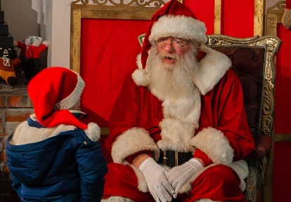 Santa Claus welcomes a young visitor to his workshop at The Village at Black Creek