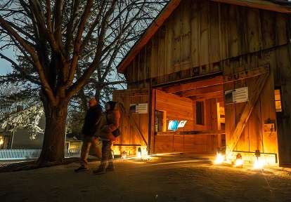 visitors explore The Village at Black Creek by lamplight during the Festive Nights holiday celebration