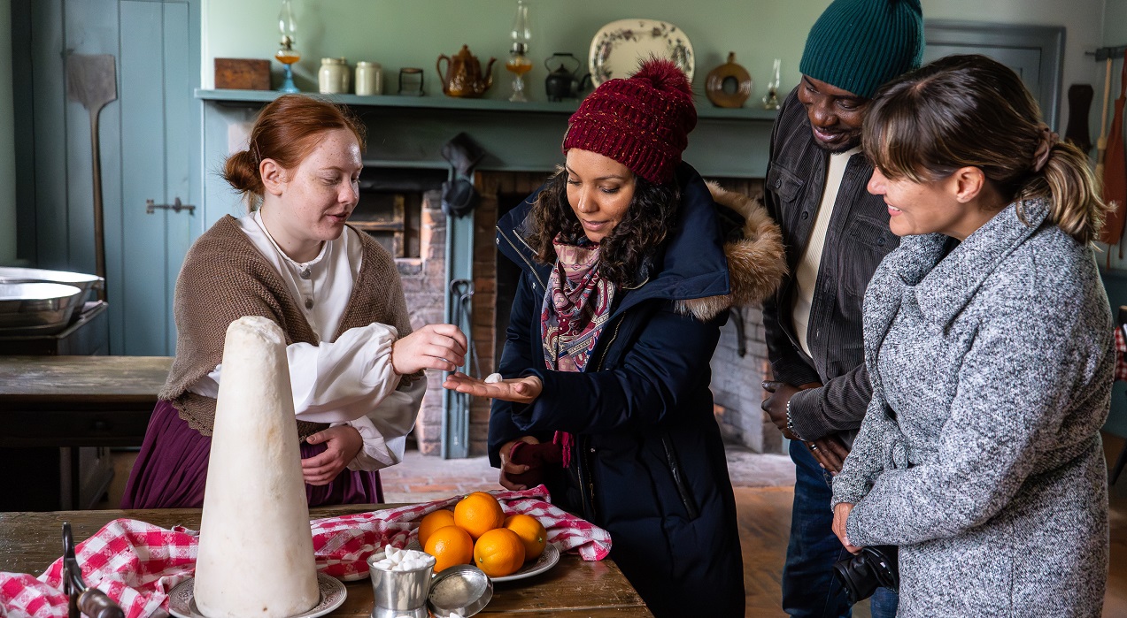 visitors learn about 19th century holiday traditions from a costumed educator during a weekday tour of The Village at Black Creek