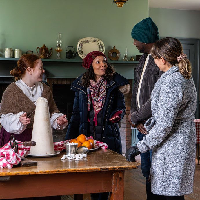 history actor explains sugar cone to visitors in the kitchen on a winter day at the Village at Black Creek