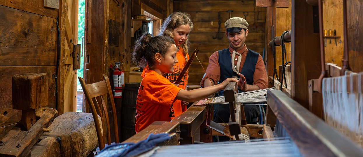 summer campers at The Village at Black Creek learn to weave using a 19th century loom