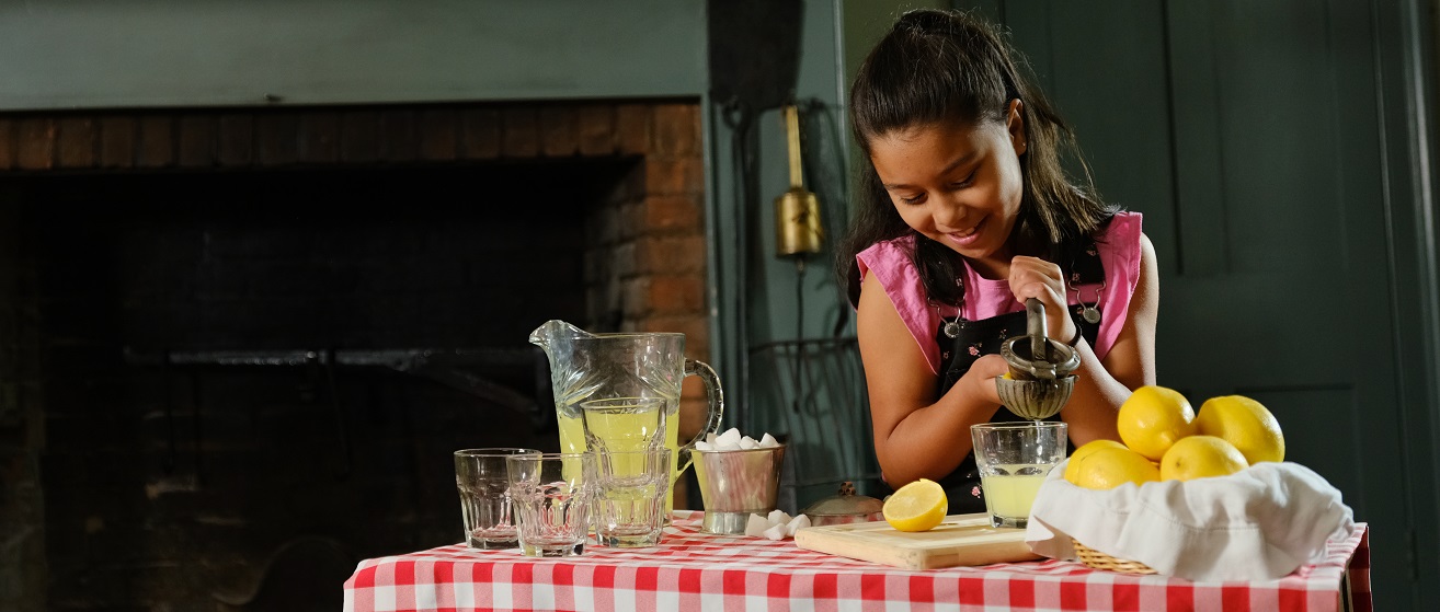 a teen summer camper at The Village at Black Creek prepares lemonade using 19th century cooking implements