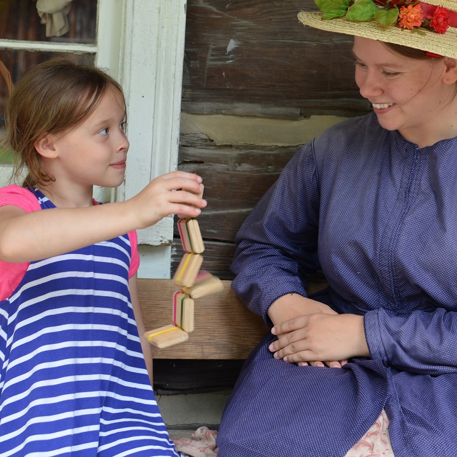 Summer Camp & Teen Experiences at The Village 1 a summer camper enjoys playing with a 19th century childrens toy at The Village at Black Creek