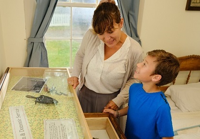 a mother and son explore an exhibit at one of the heritage buildings at The Village at Black Creek