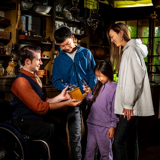 Donate 2 a costumed educator shows historic artifacts to a family of visitors at The Village at Black Creek
