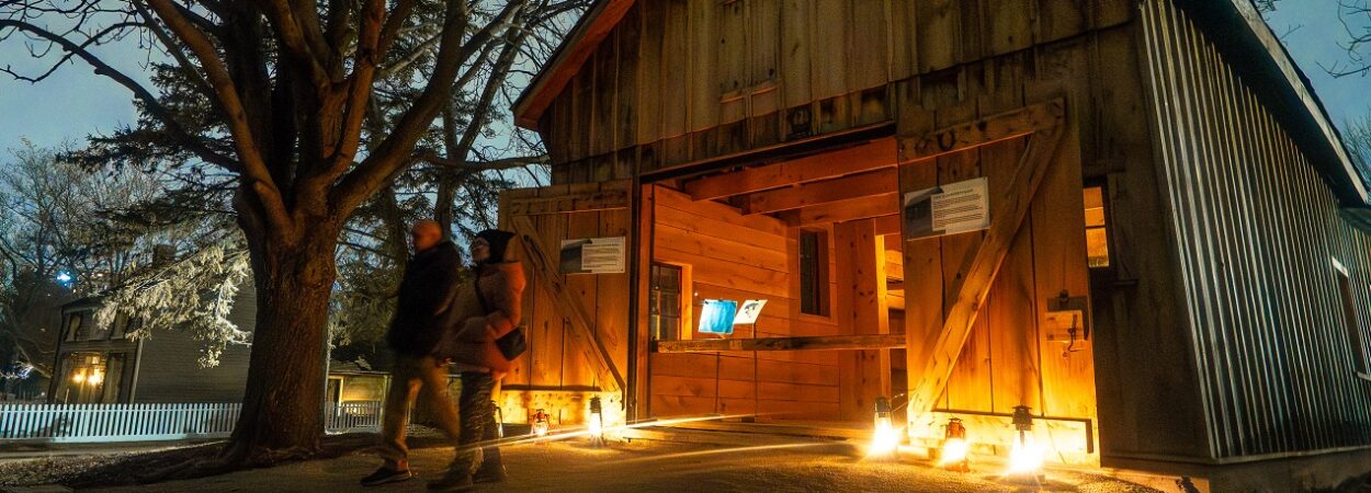 visitors explore The Village at Black Creek by lantern light during the Festive Nights event