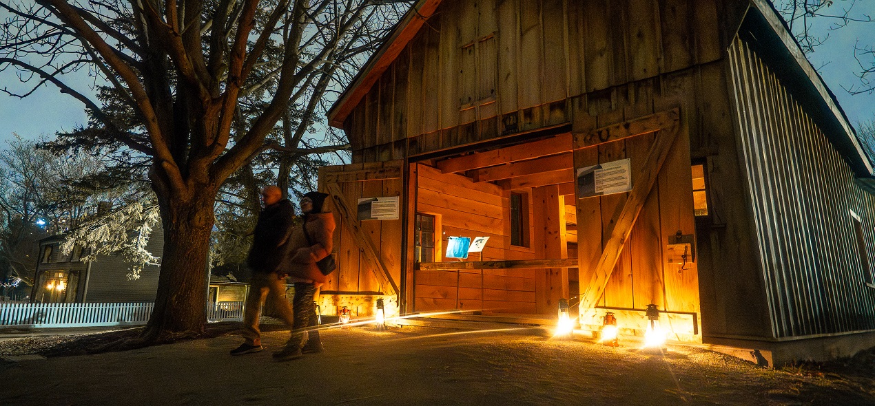 visitors explore The Village at Black Creek by lantern light during the Festive Nights event