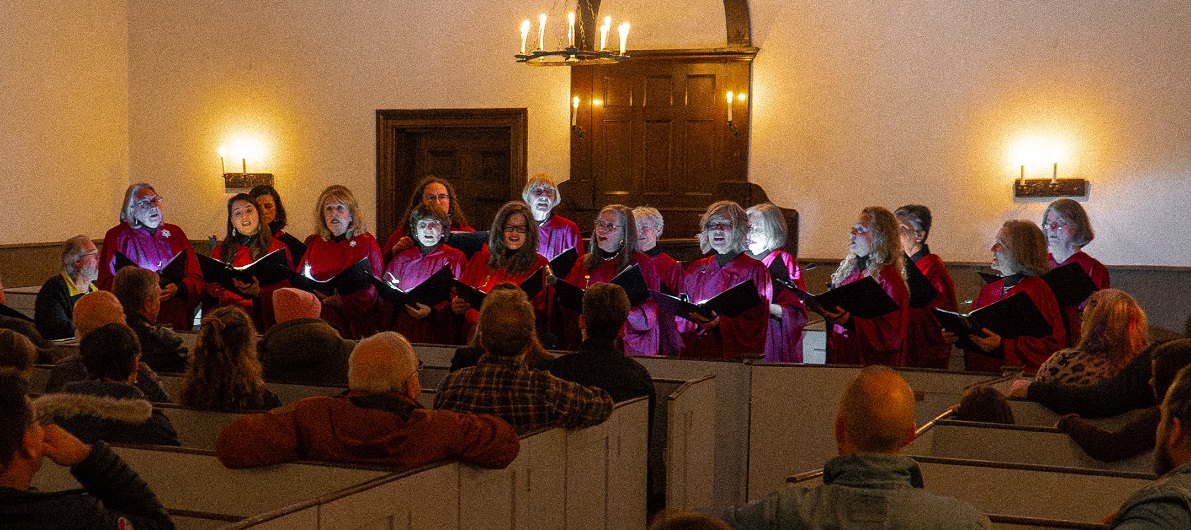 a choir performs by candlelight at the Festive Nights event at The Village at Black Creek
