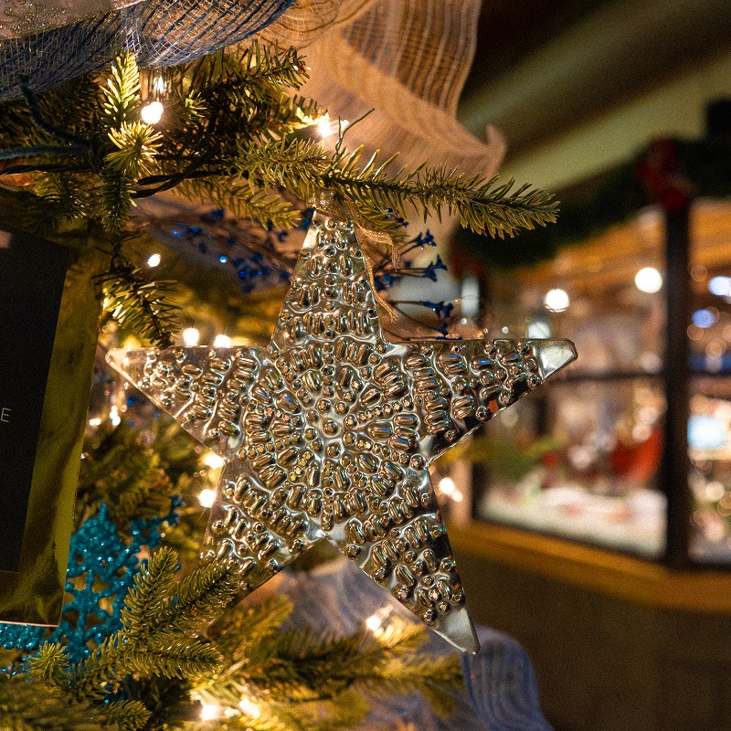 a Christmas tree is trimmed with a handmade tin holiday ornament at The Village at Black Creek