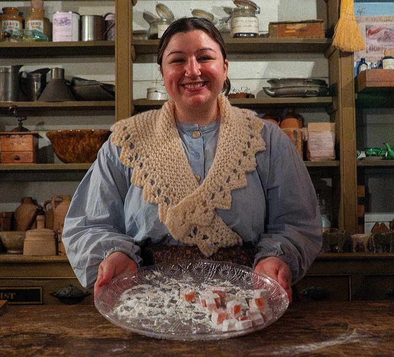 a history actor in 19th century clothing offers up a selection of traditional Victorian holiday treats at The Village at Black Creek