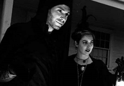 cloaked guides lead a ghost walk at night through The Village at Black Creek