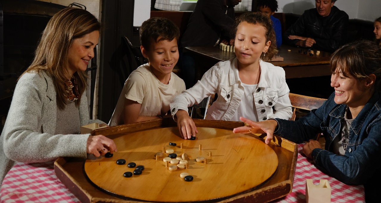 a family enjoys learning to play a Victorian board game during a weekend visit to The Village at Black Creek