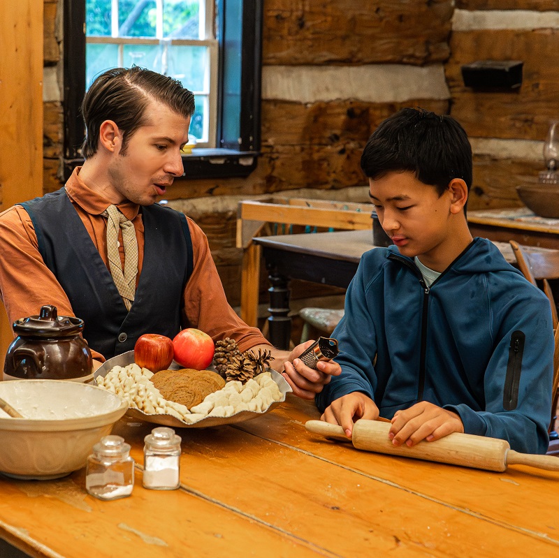Teachers, Schools & Groups 13 a costumed educator at The Village at Black Creek shows a student on a field trip how to prepare traditional Victorian holiday season delicacies