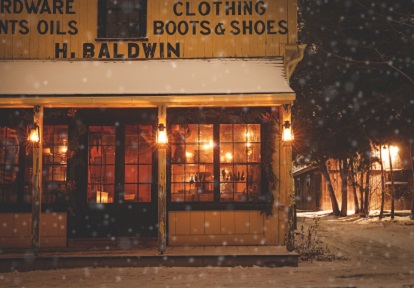 Holidays at The Village 6 snow falls on a lamp-lit street in the evening at The Village at Black Creek